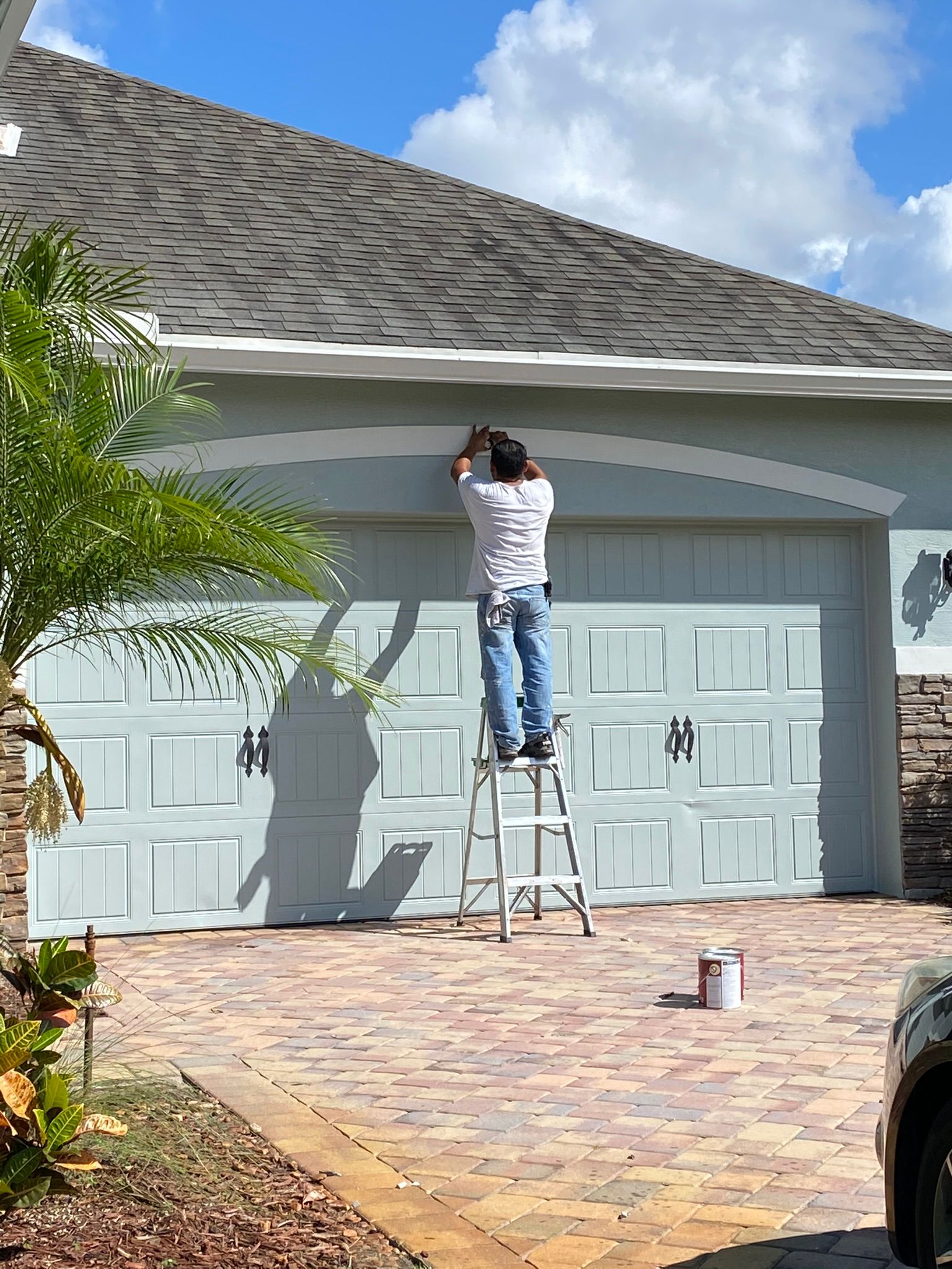 Painter on ladder taping and painting garage archway