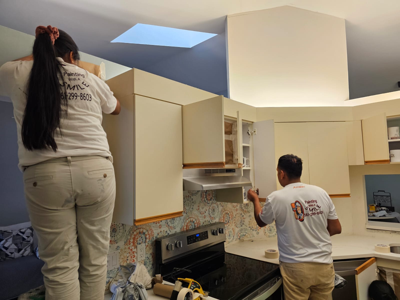Crew in branded shirts refinishing kitchen cabinets