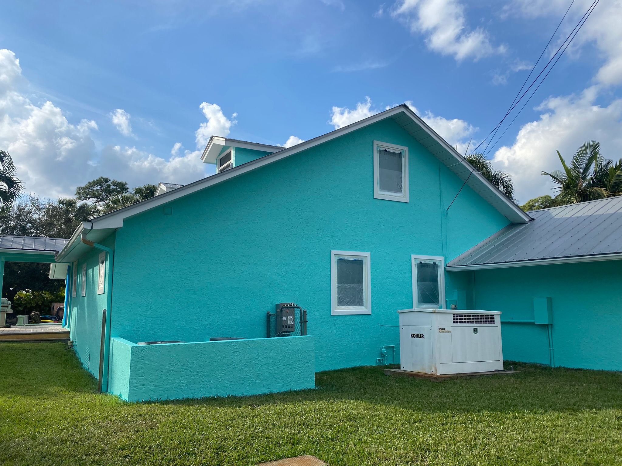 Finished teal stucco house exterior under a blue Florida sky