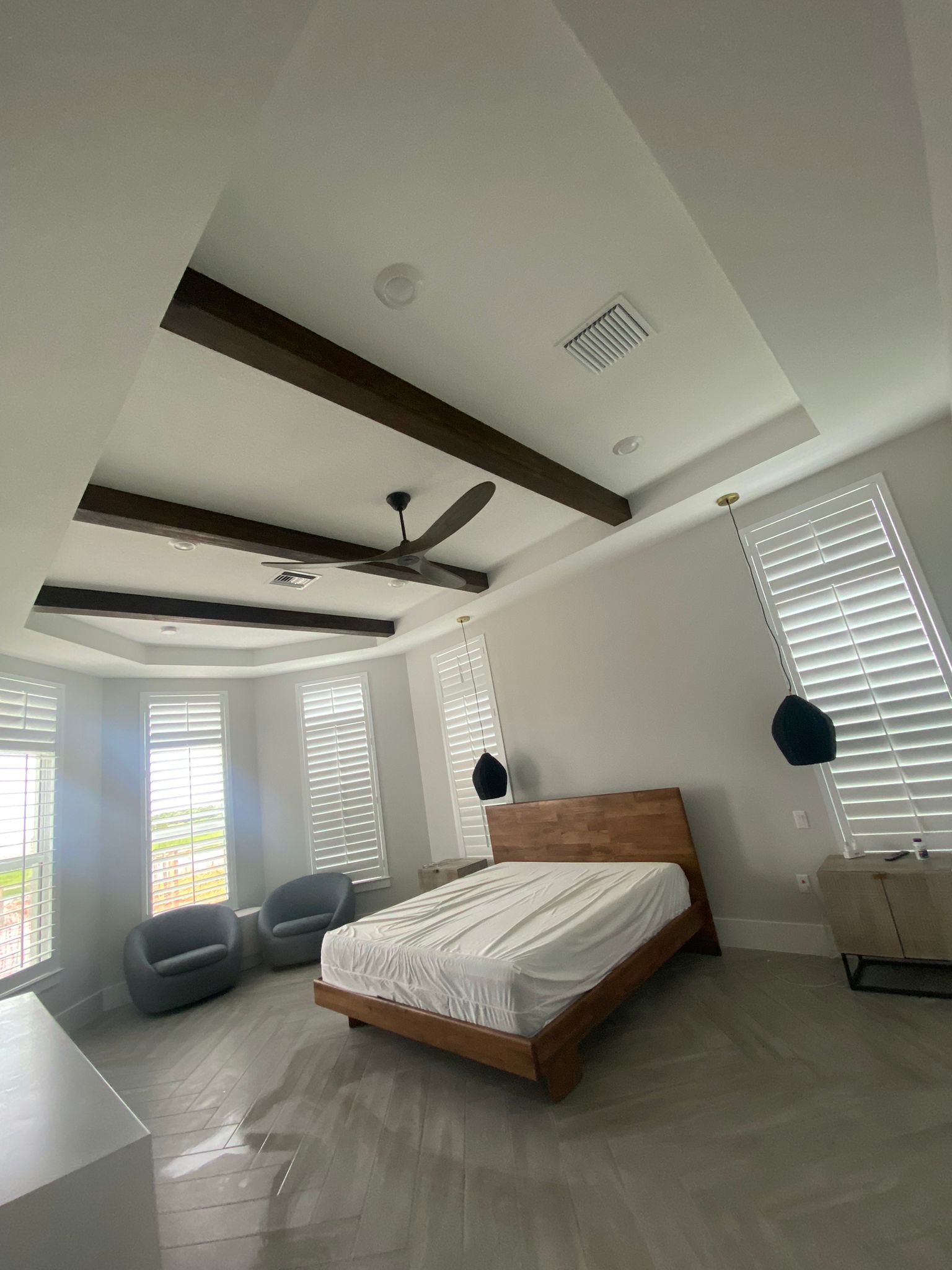 Master bedroom with wood beam tray ceiling and plantation shutters