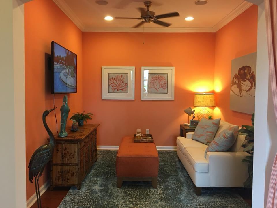 Coral orange accent den with sofa and coastal art