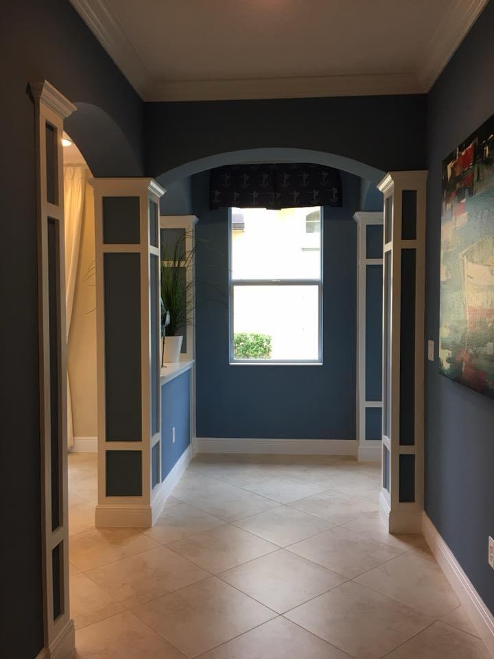 Navy blue foyer with white archways and decorative trim