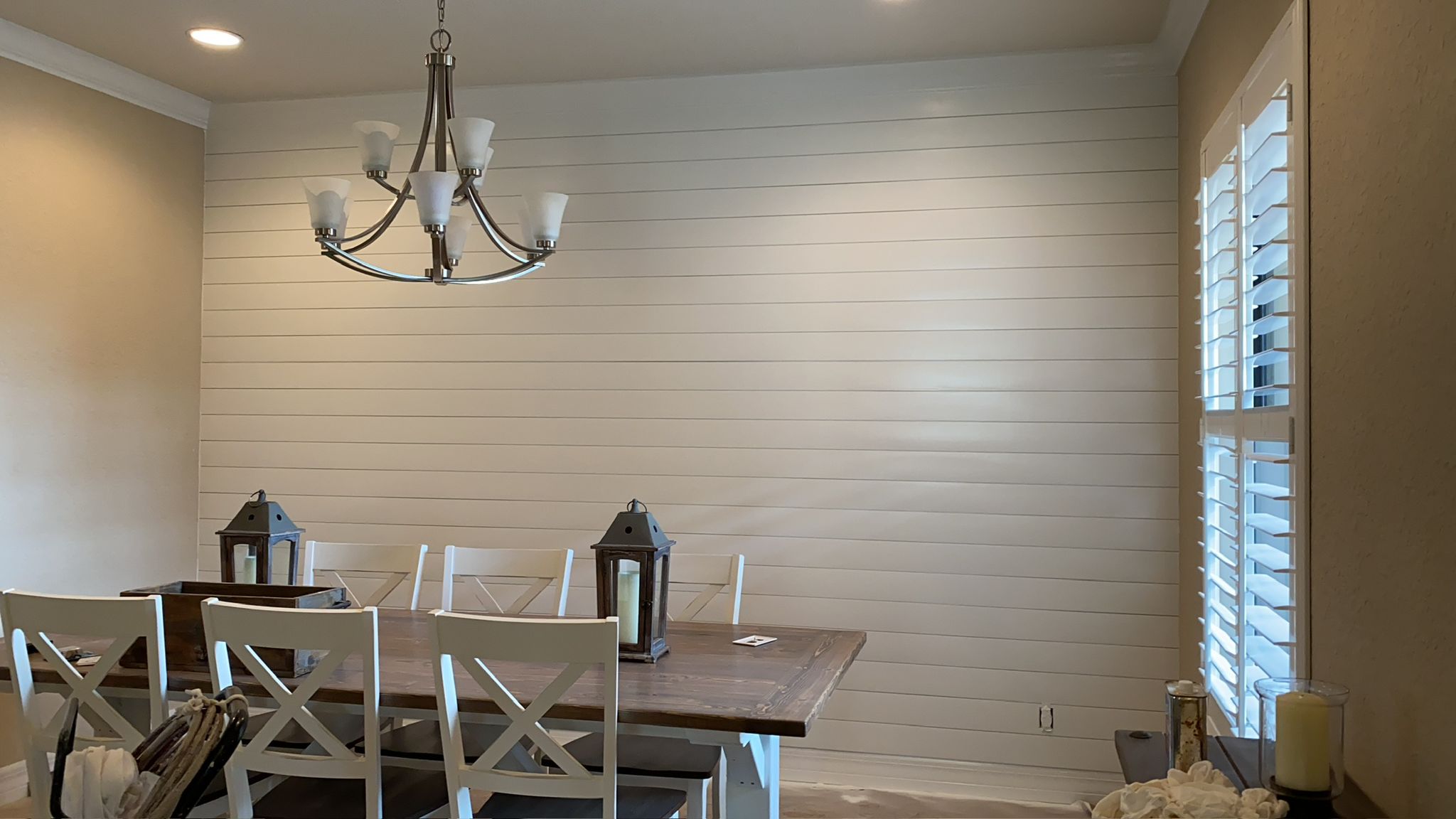 Dining room with white shiplap accent wall and chandelier