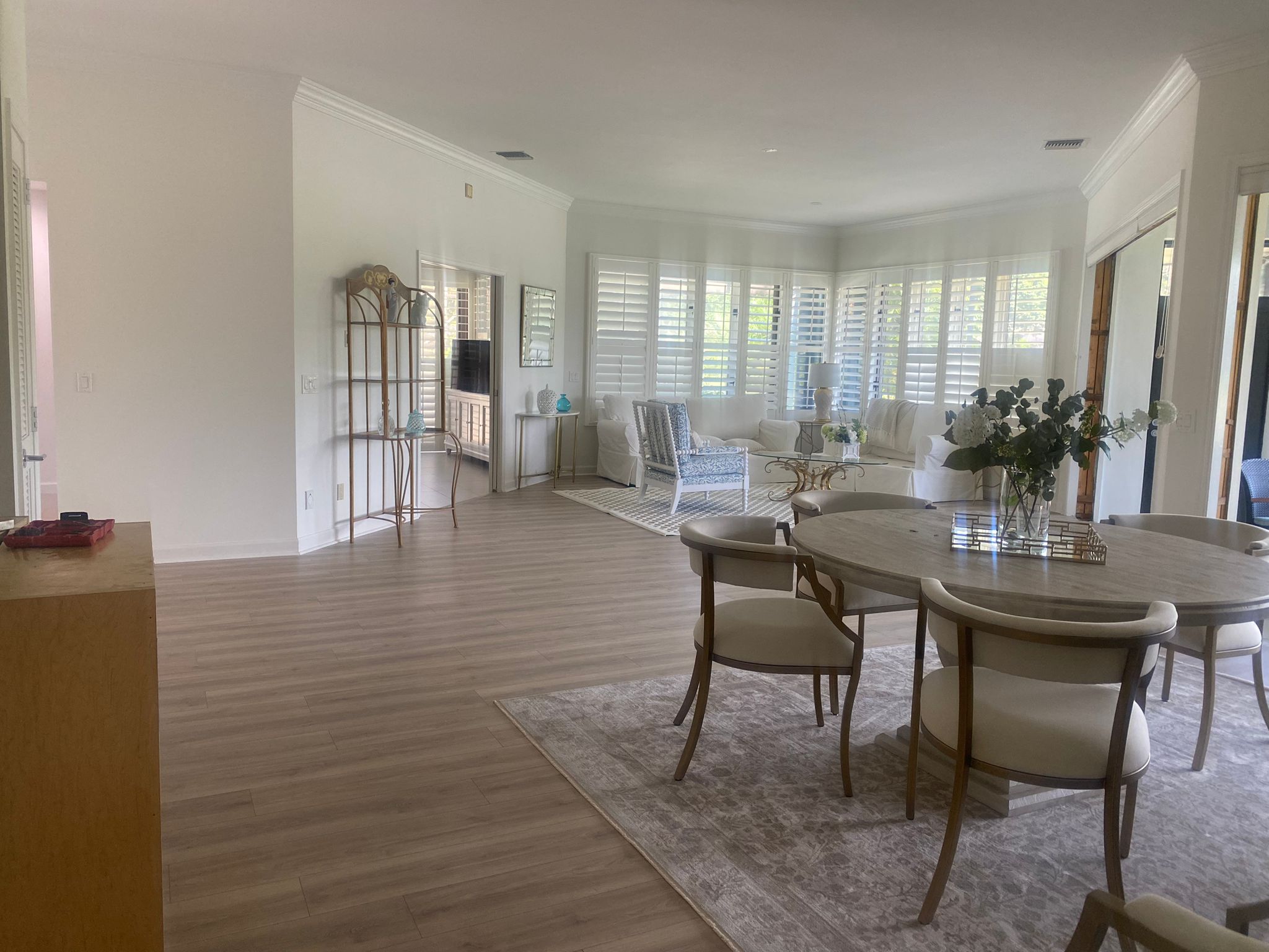 Staged open living and dining room with plantation shutters