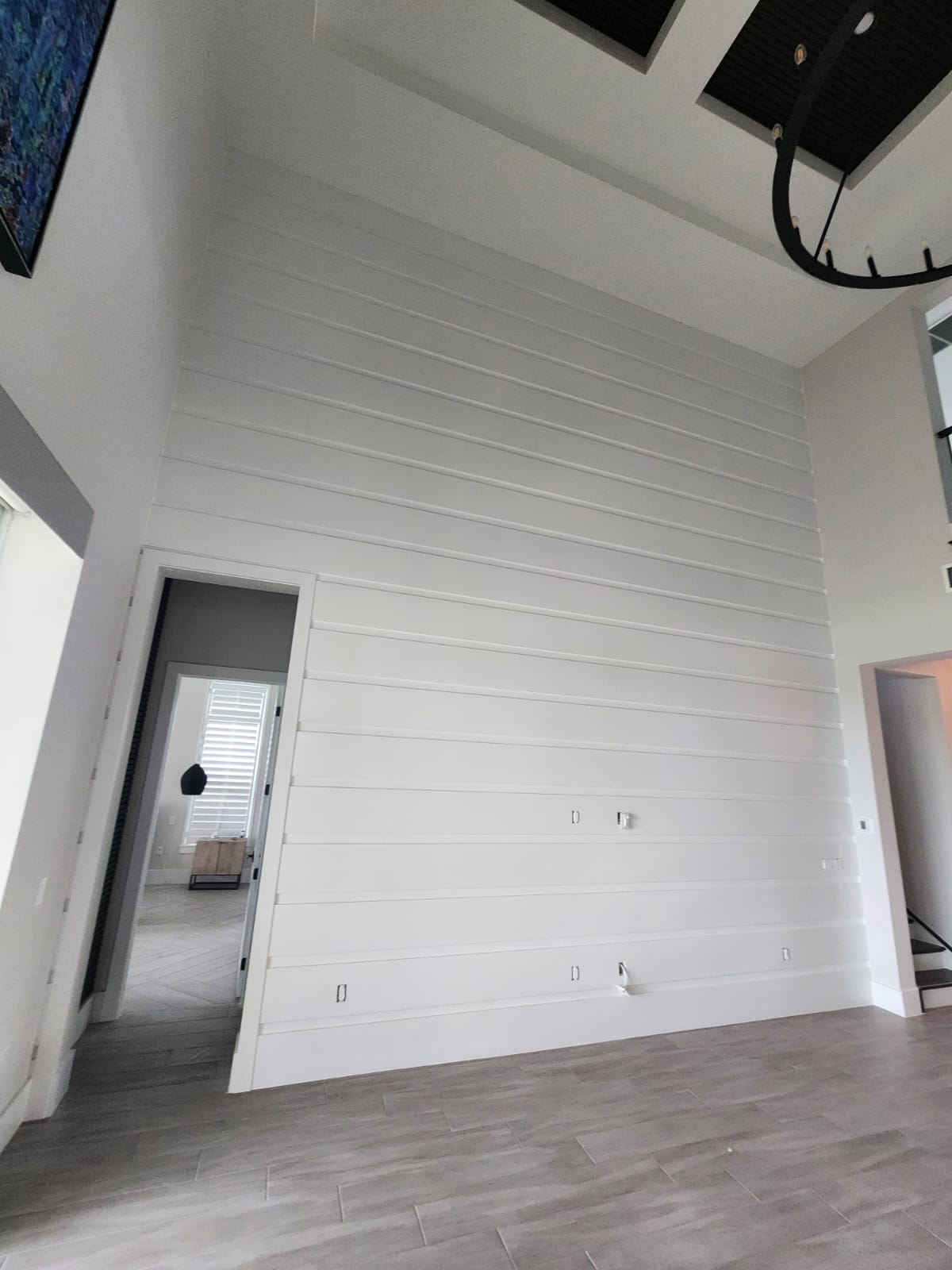 White shiplap accent wall in room with high ceiling