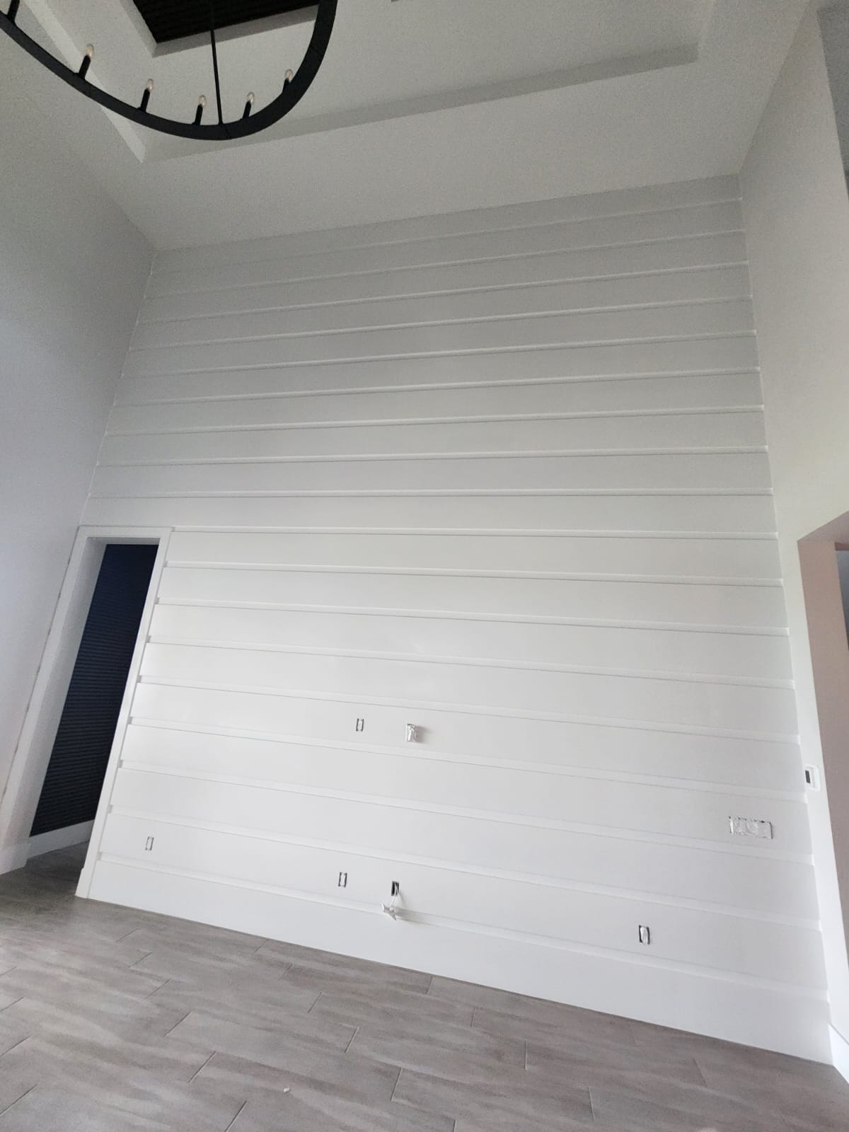Tall white shiplap feature wall with chandelier